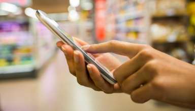 Woman using mobile phone while shopping in supermarket