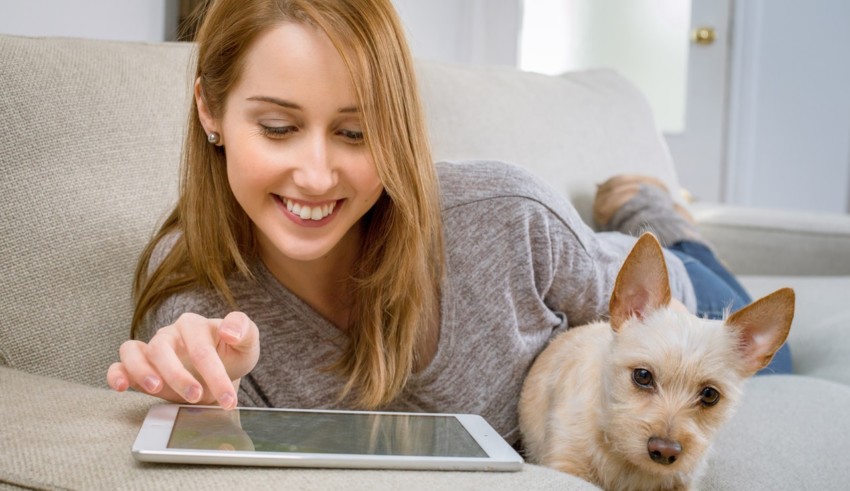 girl using tablet and sitting with dog
