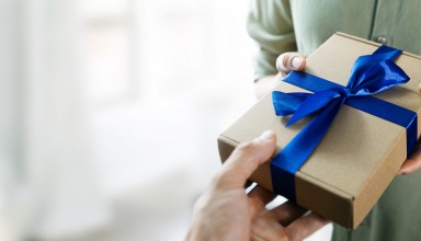 hand giving gift box with blue ribbon to a woman. copy space